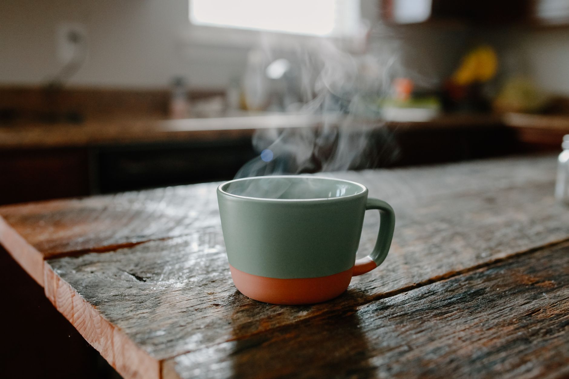 warm water health benefits – steaming cup of water on a wooden table