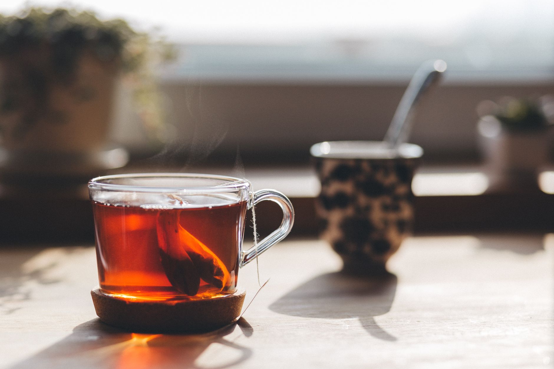 warm water TCM – steaming cup of tea on a wooden table in natural light