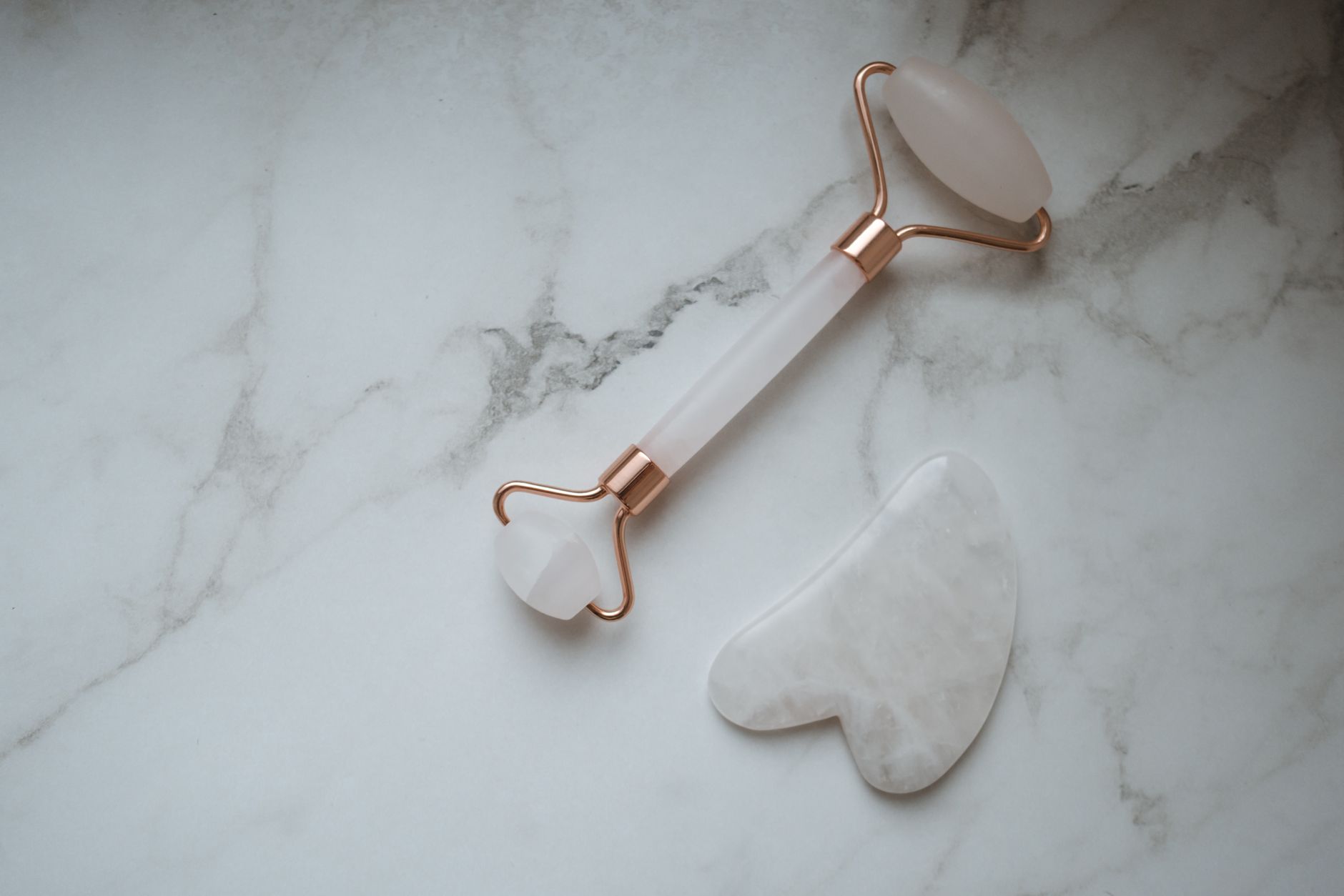 Gua Sha – stones and facial massage tools on a marble surface.