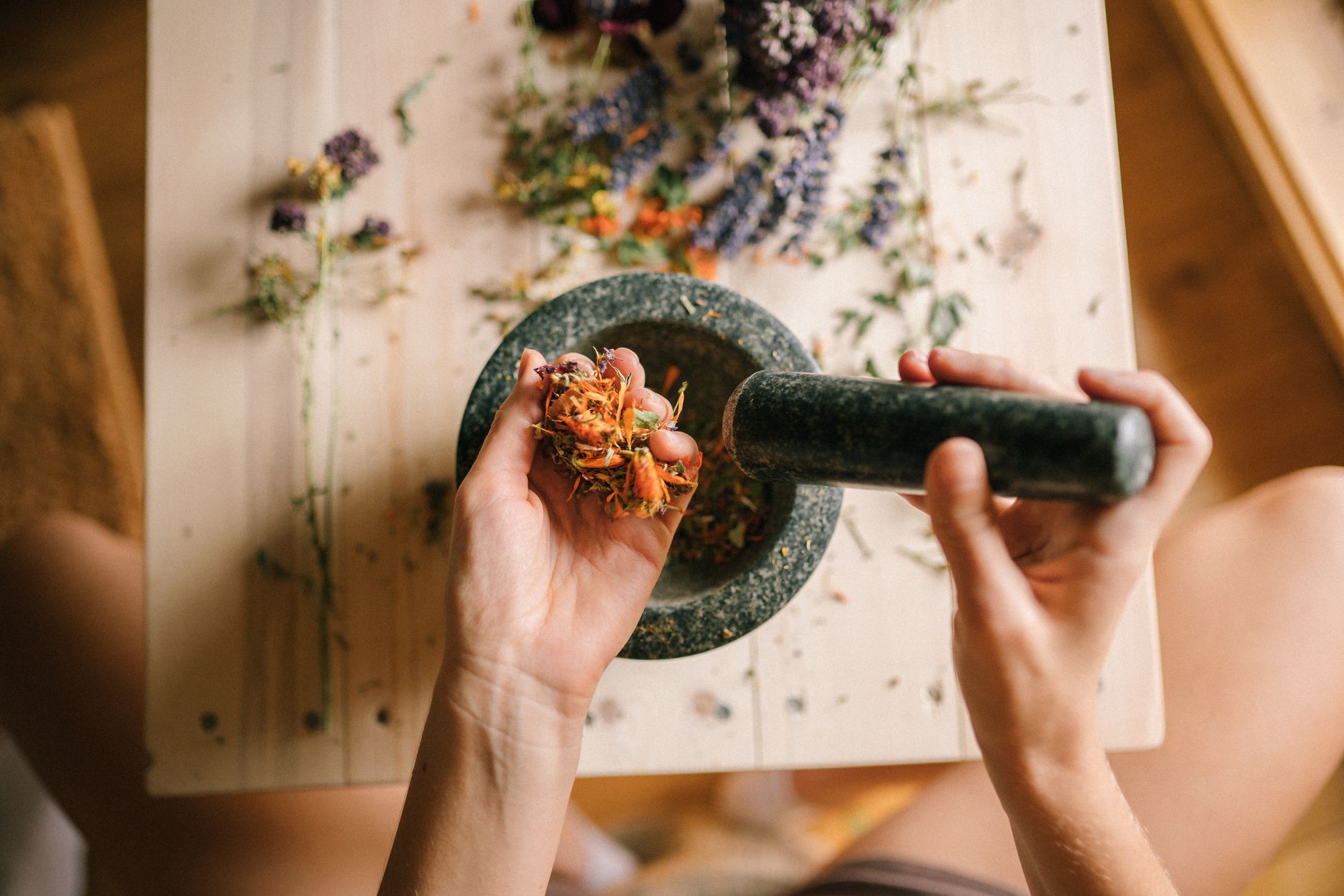 Chinese herbal tea – person drinking it with medicinal herbs on table.