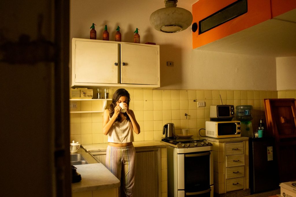 warm water health benefits – person drinking warm water in cozy kitchen