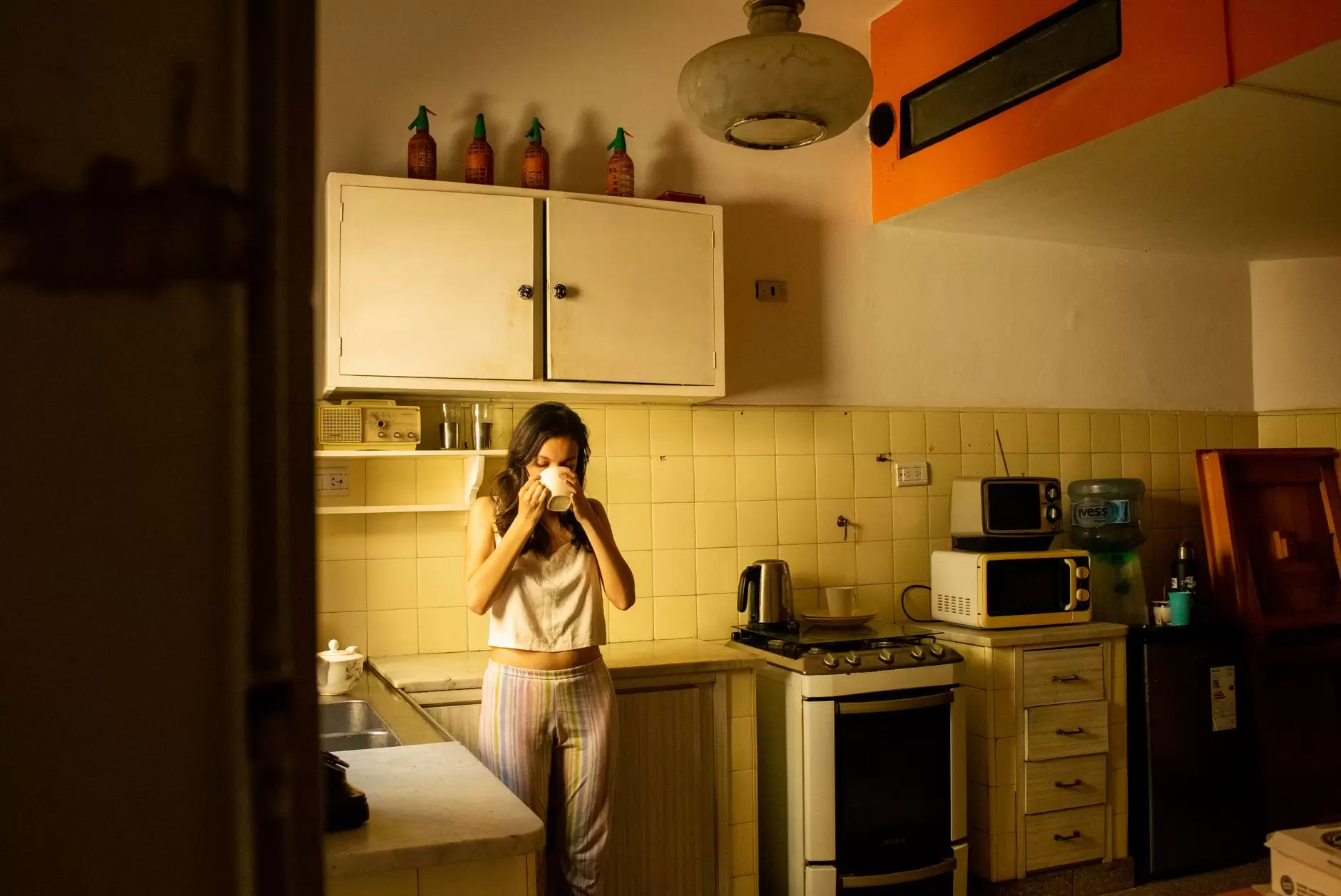 warm water health benefits – person drinking warm water in cozy kitchen
