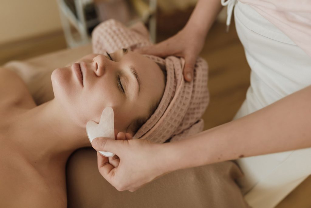 gua sha marks meaning – woman receiving facial treatment with red marks