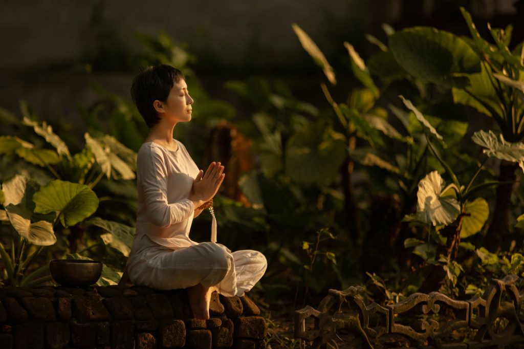 What is Qi – person meditating in a serene garden at sunrise.