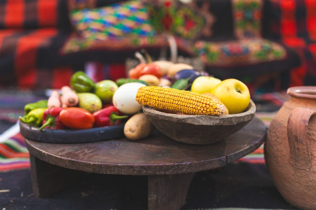 TCM food energetics – fresh vegetables and fruits on a wooden table in natural light.