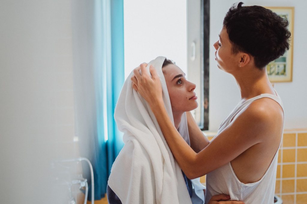 wet hair sleep – woman drying her hair with a towel in a bathroom.